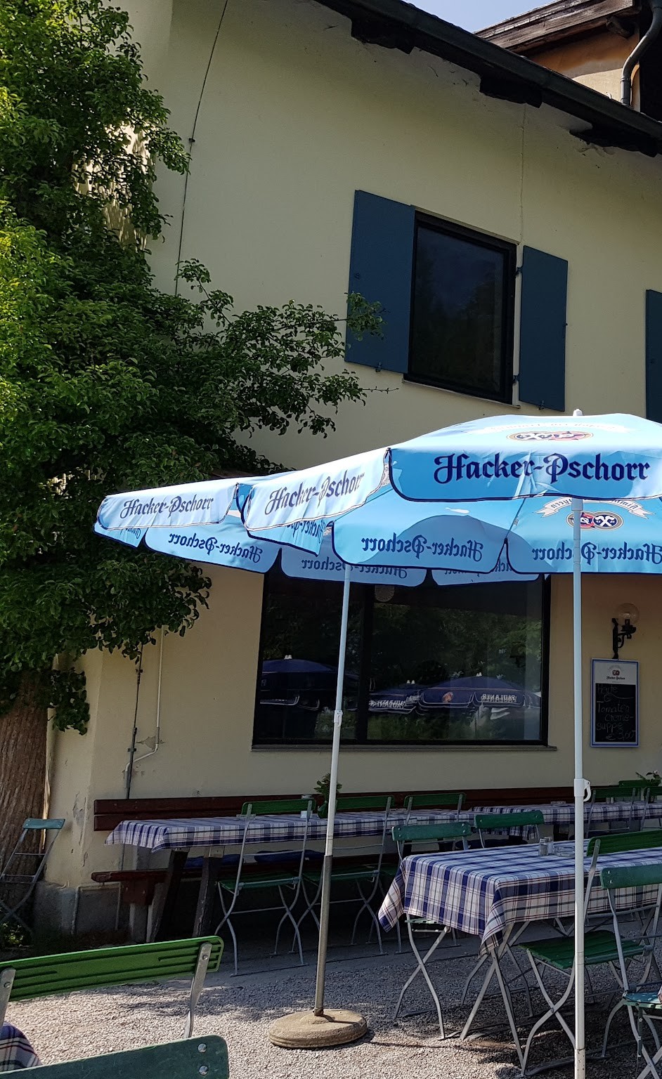 Das Haus des Gasthofs Seeseiten mit Hacker-Pschorr-Schirmen im Biergarten